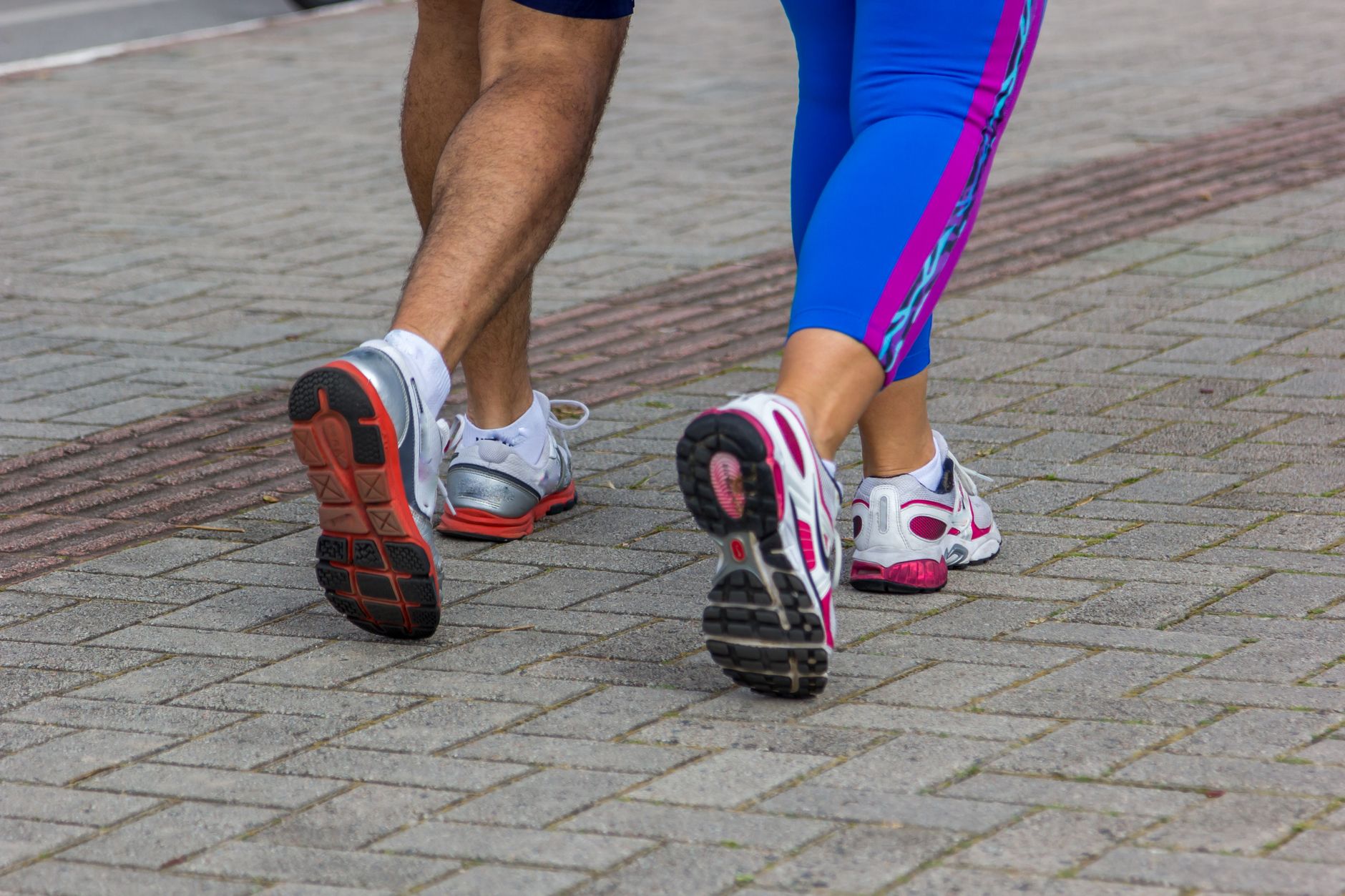 close up of man and woman in sportswear running on the sidewalk
